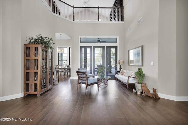 foyer entrance with ceiling fan, a towering ceiling, and dark hardwood / wood-style floors