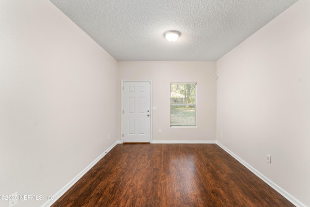 spare room with dark wood-type flooring and a textured ceiling