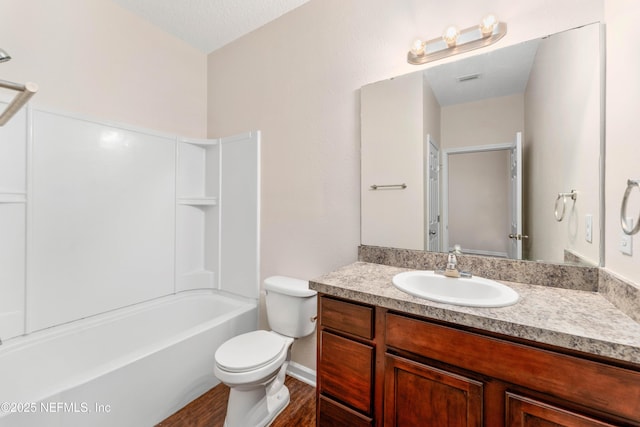 full bathroom featuring vanity, wood-type flooring, a textured ceiling, bathtub / shower combination, and toilet