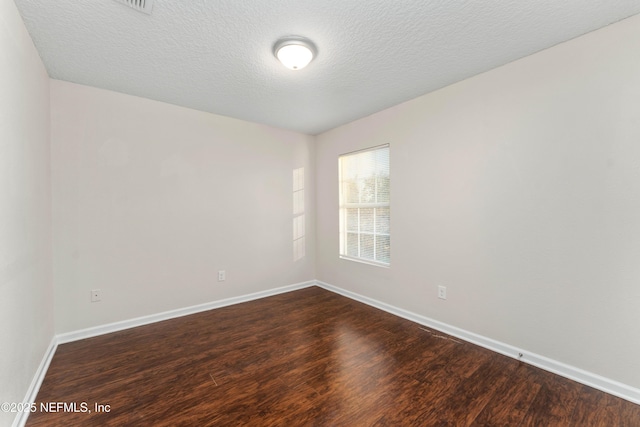 empty room featuring dark hardwood / wood-style flooring and a textured ceiling