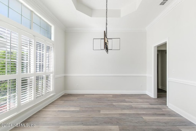 unfurnished dining area with a raised ceiling and light wood-type flooring