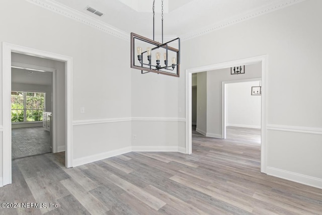 unfurnished dining area featuring ornamental molding, a chandelier, and light wood-type flooring