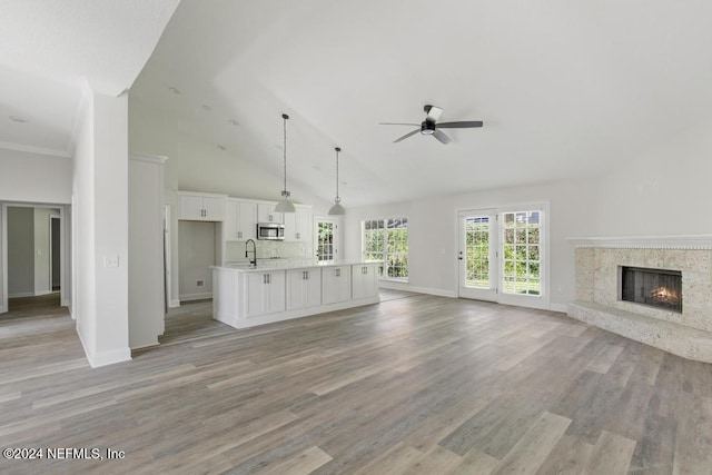 unfurnished living room with sink, high vaulted ceiling, light hardwood / wood-style flooring, ceiling fan, and a premium fireplace