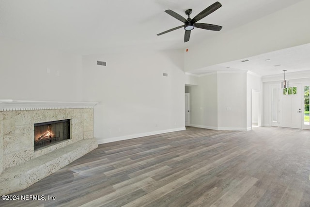 unfurnished living room featuring crown molding, wood-type flooring, vaulted ceiling, ceiling fan, and a high end fireplace