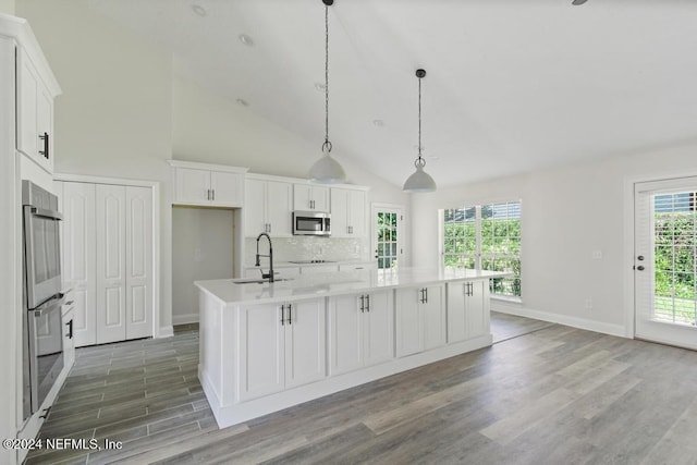 kitchen with pendant lighting, sink, white cabinetry, stainless steel appliances, and an island with sink