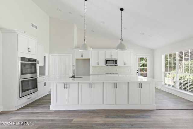 kitchen featuring stainless steel appliances, a kitchen island with sink, white cabinets, and decorative light fixtures