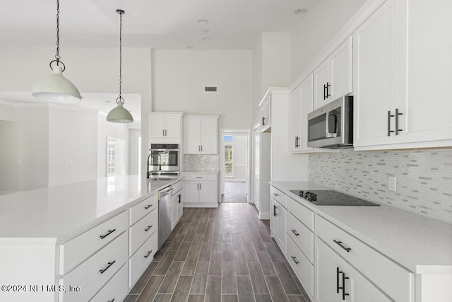 kitchen featuring white cabinetry, sink, hanging light fixtures, stainless steel appliances, and a center island with sink