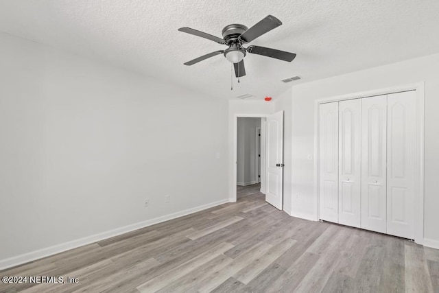 unfurnished bedroom featuring a closet, ceiling fan, a textured ceiling, and light hardwood / wood-style flooring