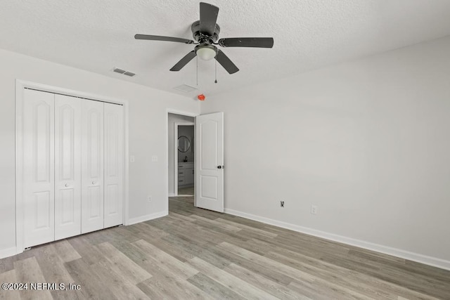 unfurnished bedroom with ceiling fan, a textured ceiling, light wood-type flooring, and a closet