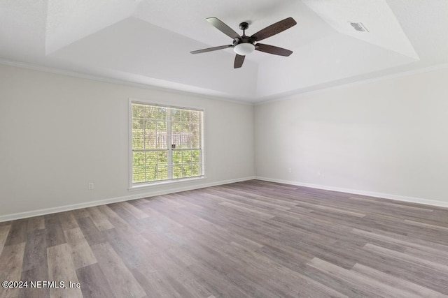 unfurnished room with ceiling fan, ornamental molding, a raised ceiling, and light hardwood / wood-style flooring