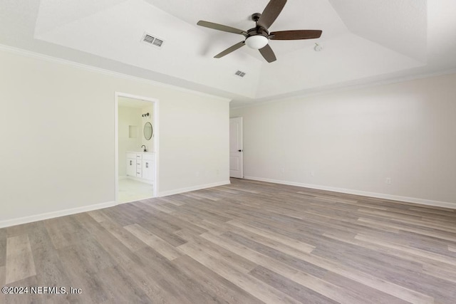 spare room featuring crown molding, light hardwood / wood-style floors, and a tray ceiling