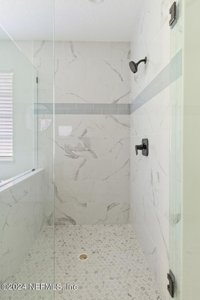 bathroom with a shower with shower door and a textured ceiling