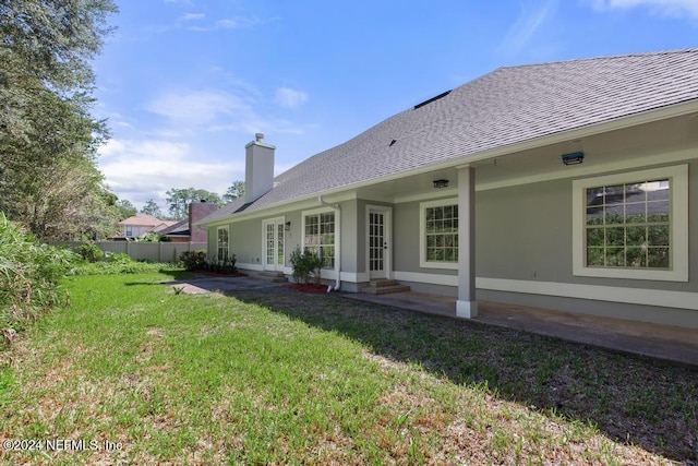 back of property featuring french doors and a lawn