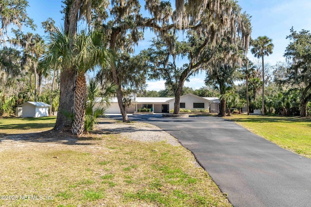 ranch-style home featuring aphalt driveway and a front lawn