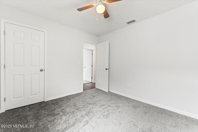 unfurnished bedroom featuring ceiling fan, dark carpet, and a textured ceiling