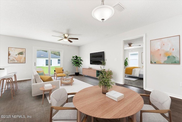 living room featuring ceiling fan, dark wood-type flooring, and a textured ceiling