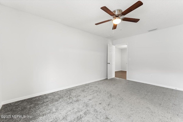 empty room with ceiling fan and dark colored carpet