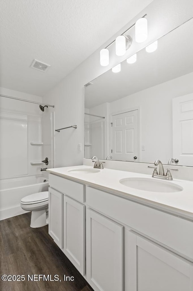 full bathroom with toilet, bathing tub / shower combination, wood-type flooring, a textured ceiling, and vanity