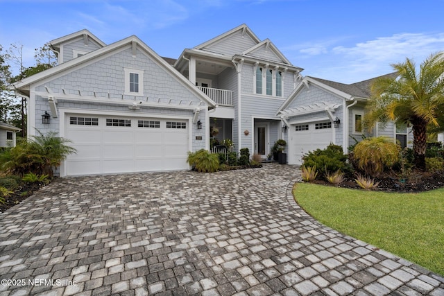 view of front of property featuring a balcony, a garage, and a front lawn