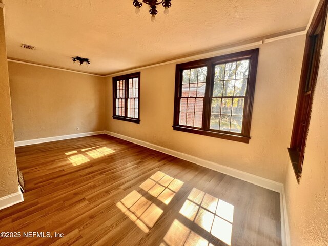 spare room with crown molding, hardwood / wood-style flooring, and a textured ceiling