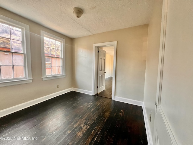 unfurnished room featuring dark wood-type flooring and a textured ceiling