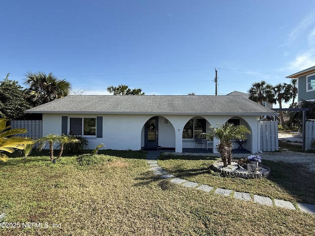 ranch-style home featuring a front yard, roof with shingles, and stucco siding