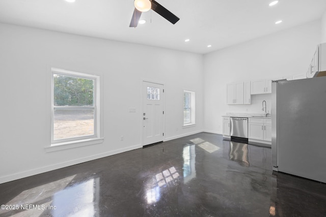 unfurnished living room featuring sink, a towering ceiling, and ceiling fan