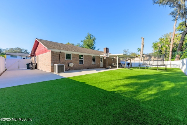 back of house with a trampoline, central AC unit, a yard, and a patio