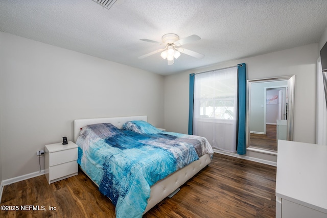 bedroom with ceiling fan, dark wood-type flooring, and a textured ceiling