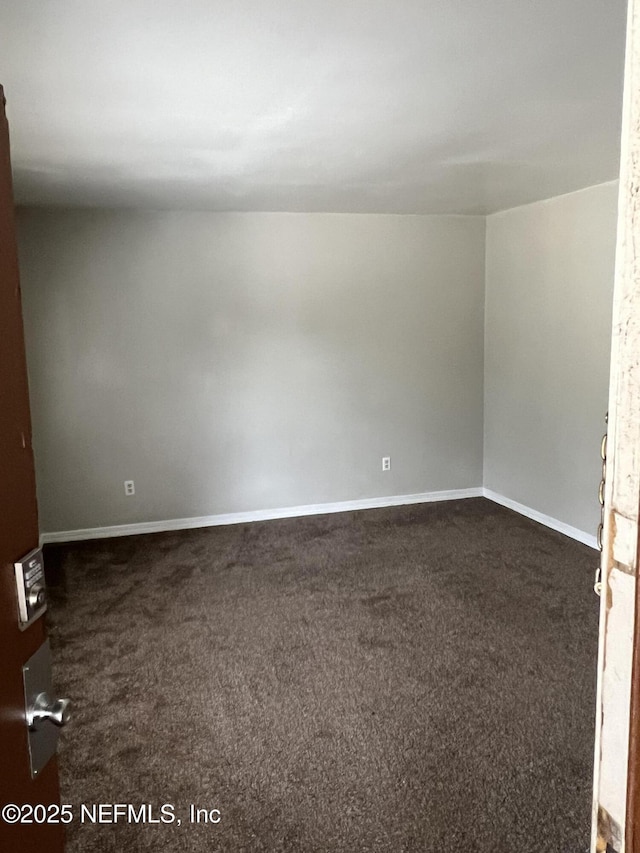 spare room with dark carpet