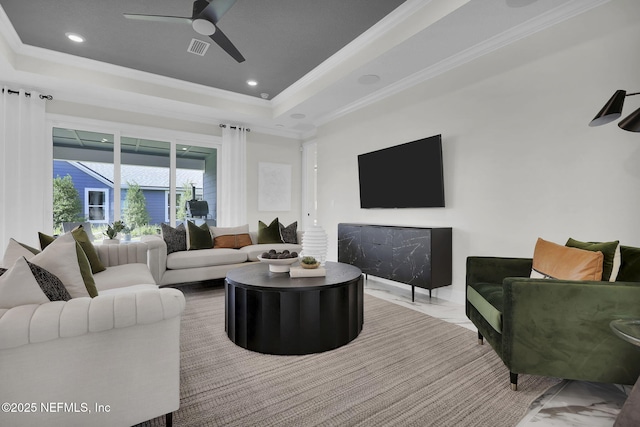 living room featuring a raised ceiling, crown molding, and ceiling fan