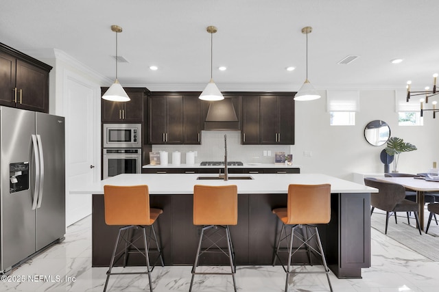 kitchen with stainless steel appliances, hanging light fixtures, and a kitchen island with sink