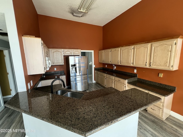 kitchen featuring high vaulted ceiling, sink, range, kitchen peninsula, and stainless steel refrigerator with ice dispenser