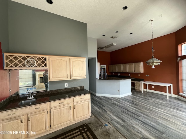 kitchen with light brown cabinetry, sink, decorative light fixtures, dark hardwood / wood-style flooring, and a high ceiling