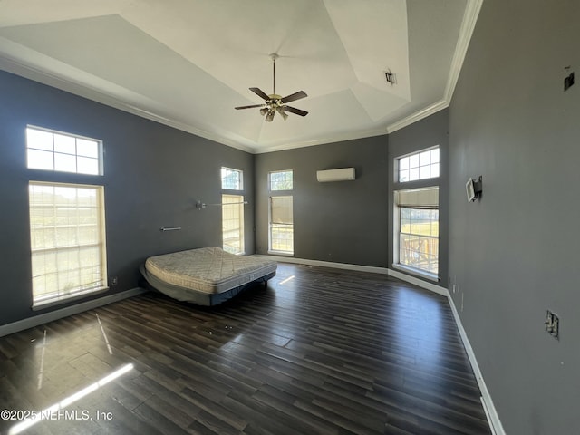 unfurnished bedroom featuring crown molding, an AC wall unit, a tray ceiling, dark hardwood / wood-style flooring, and a towering ceiling