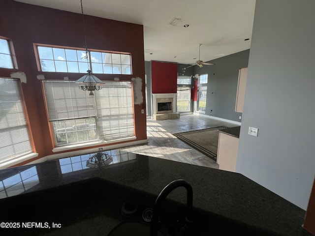 kitchen with a tile fireplace, ceiling fan, and decorative light fixtures