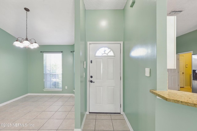 tiled foyer featuring an inviting chandelier and a textured ceiling