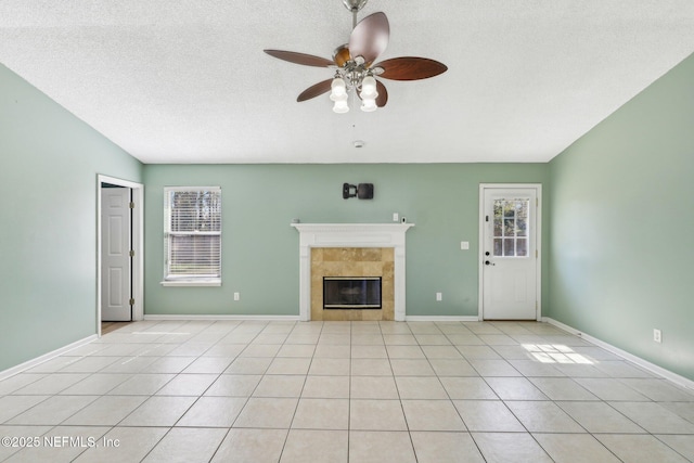 unfurnished living room with light tile patterned flooring, ceiling fan, plenty of natural light, and a tiled fireplace