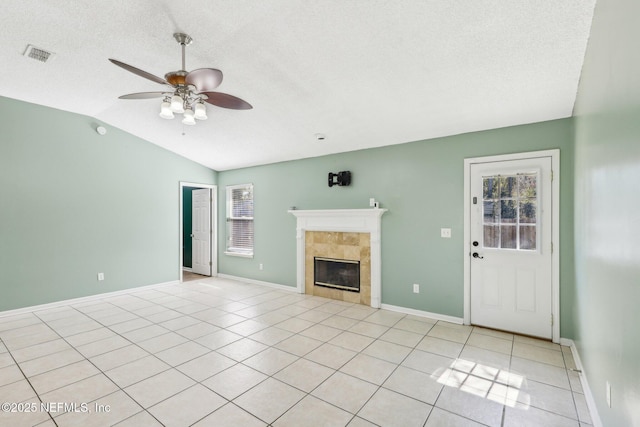 unfurnished living room with lofted ceiling, light tile patterned floors, a tiled fireplace, and a textured ceiling