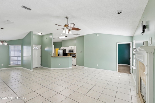 unfurnished living room with light tile patterned floors, ceiling fan with notable chandelier, vaulted ceiling, and a textured ceiling