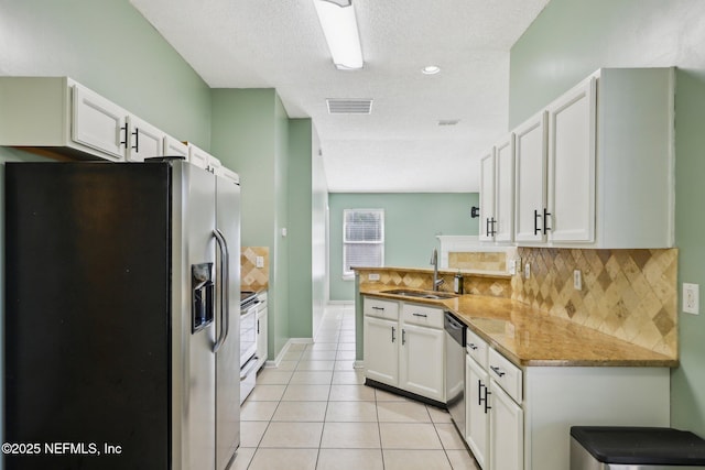 kitchen with sink, light tile patterned floors, appliances with stainless steel finishes, kitchen peninsula, and white cabinets