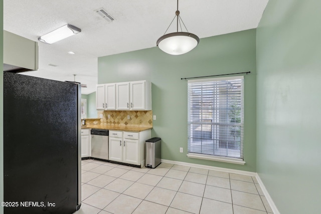 kitchen featuring black fridge, hanging light fixtures, stainless steel dishwasher, white cabinets, and backsplash