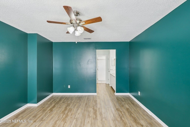 spare room featuring ceiling fan, light hardwood / wood-style flooring, and a textured ceiling