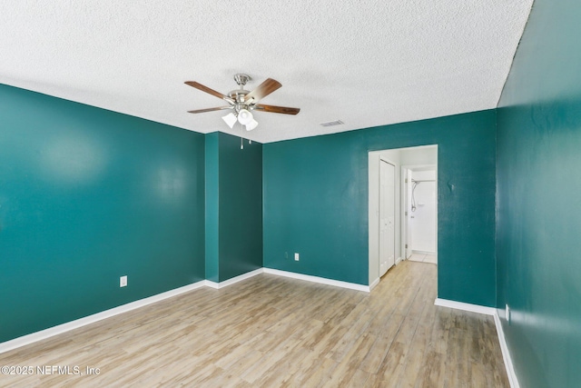 empty room with ceiling fan, a textured ceiling, and light hardwood / wood-style floors