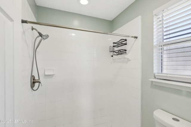 bathroom with tiled shower and toilet