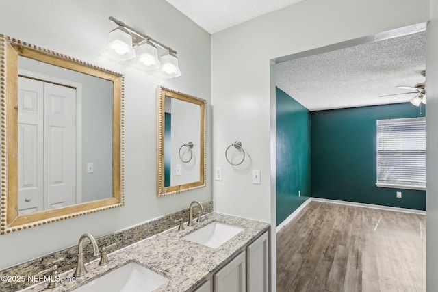 bathroom featuring hardwood / wood-style flooring, ceiling fan, vanity, and a textured ceiling