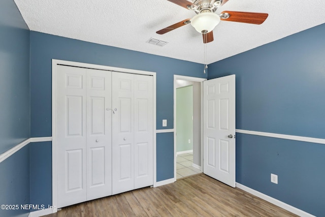 unfurnished bedroom with ceiling fan, hardwood / wood-style floors, a textured ceiling, and a closet