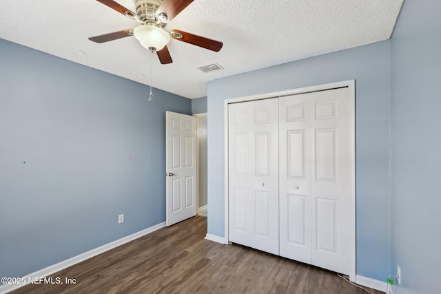 unfurnished bedroom with dark wood-type flooring, a closet, ceiling fan, and a textured ceiling