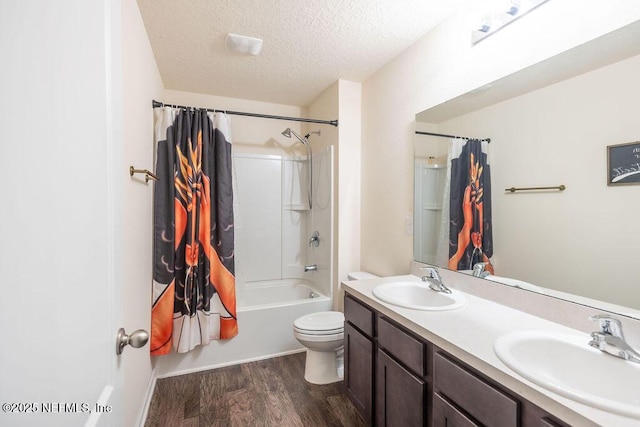 full bathroom featuring shower / bath combo, vanity, wood-type flooring, a textured ceiling, and toilet