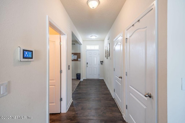 hallway with dark hardwood / wood-style floors and a textured ceiling